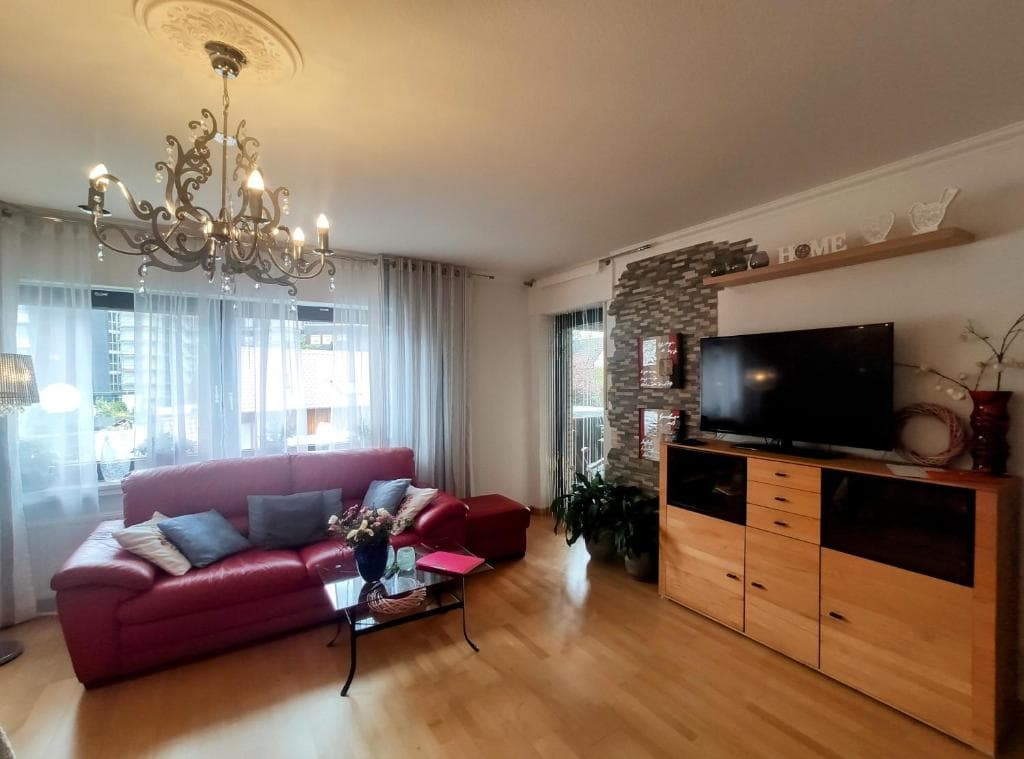 Erholungs Apartment - Wohnzimmer mit TV, Steinwand und Balkonzugang