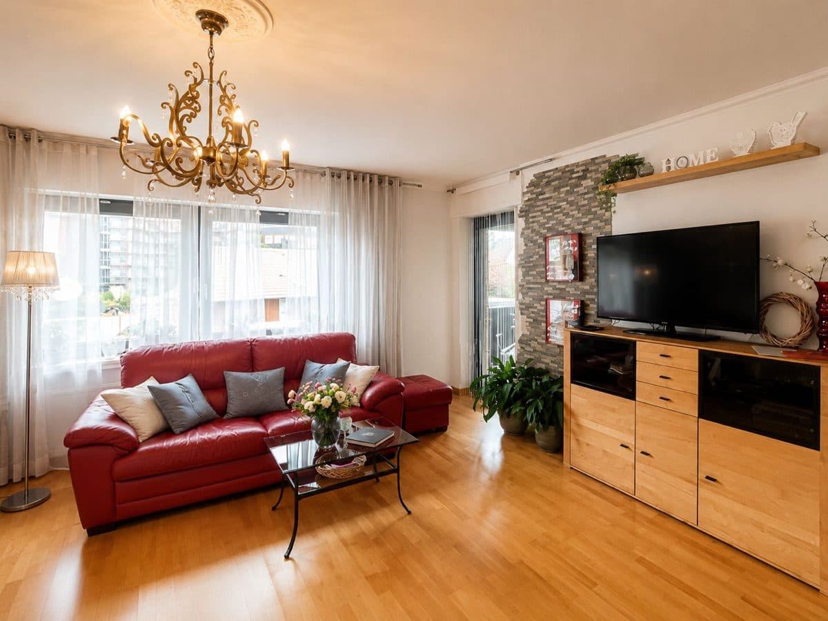 Erholungs Apartment - Schlafbereich mit Bett, Kronleuchter und Loungesofa am Fenster